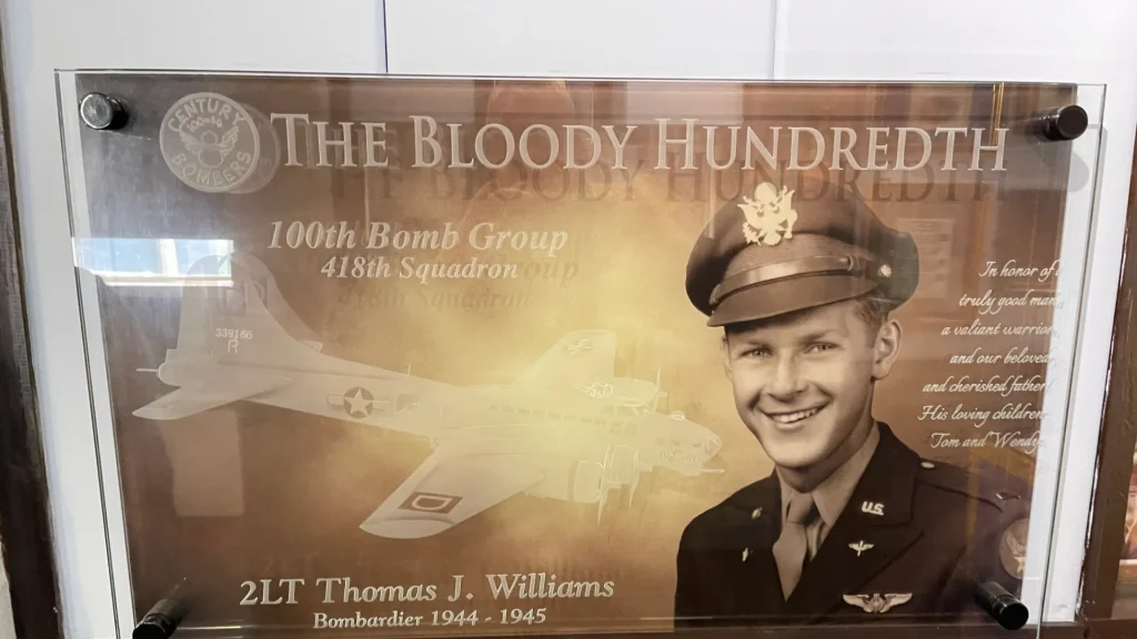 Exhibit display featuring an image of 2lt thomas j. williams, a bombardier from 1944-1945, with background graphics related to the 100th bomb group, 418th squadron, nicknamed "the bloody hundredth.