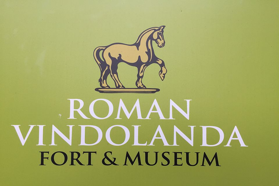 Logo of roman vindolanda featuring a silhouette of a horse on a pedestal, with the text "roman vindolanda fort & museum" on a green background.