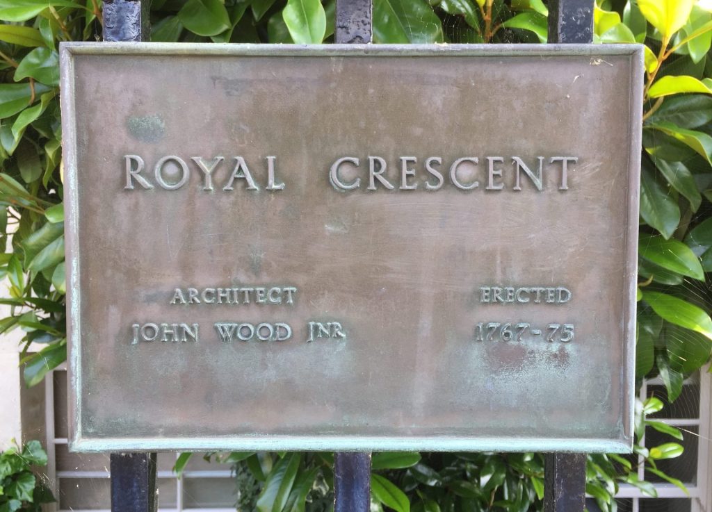 Bronze plaque with the inscription "royal crescent, architect john wood inr, erected 1767-75" mounted on a green foliage background.