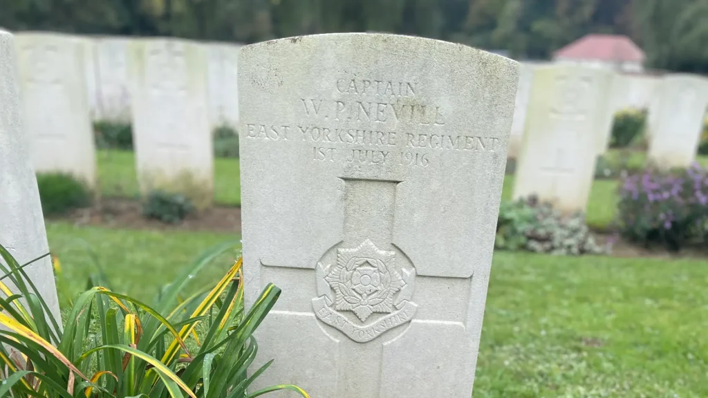 A grave marker with the inscription "captain w.p. nevill, east yorkshire regiment, 1st july 1916" surrounded by rows of similar headstones and green vegetation.