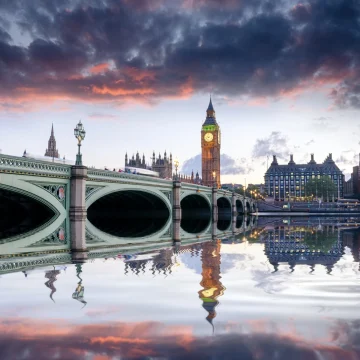Westminster bridge and the big ben at sunset, with colorful skies and a clear reflection of the landmarks on the river thames in london.