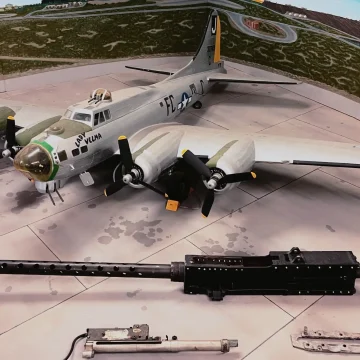 A model of a vintage military aircraft with four propellers, displayed in a diorama setting that includes miniature vehicles, equipment, and a painted background depicting a landscape.