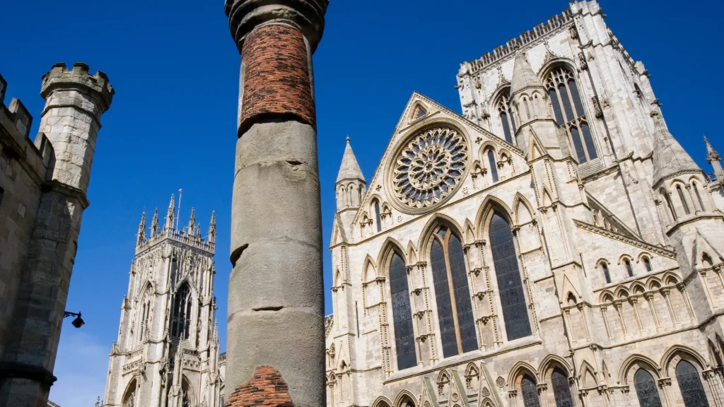 Ancient cathedral with intricate gothic architecture, featuring a large rose window and decorative stone spires under a clear blue sky.